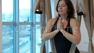 有魅力的女人在室内的工作室里冥想帕德马萨纳姿势吊床。